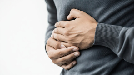 Obraz premium person holding their stomach, indicating discomfort or pain, wearing gray sweater. focus is on hands and area of concern, conveying sense of unease