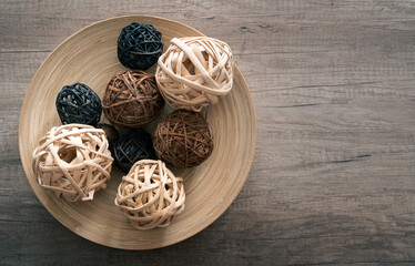 Decorative wicker balls in wooden bowl on rustic table with copy space.