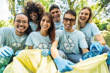 Group of volunteer cleaning picking up plastic litter in the park - Diverse group of people collect...