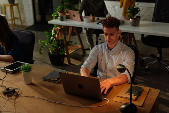 Focused employee working late at night in the office using laptop