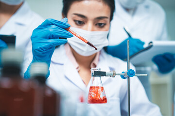 A scientist carefully drops a red solution into a flask, creating swirling patterns, symbolizing precision, innovation, and the critical role of laboratory research in advancing medical science.