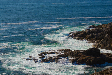 The blue ocean beats with waves against the rocks