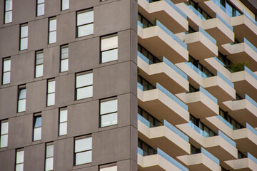 Modern residential building with unique architectural design featuring a mix of dark facade and light balconies, showcasing contemporary urban living and innovative construction techniques