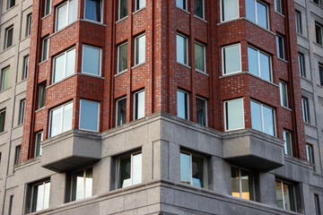 Modern architectural building featuring a unique blend of brick and concrete materials, showcasing large windows and geometric design elements in an urban environment