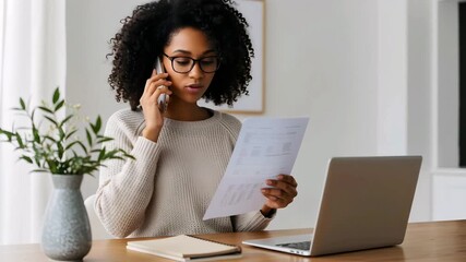 Woman on Phone Call with Documents at Home professional woman with curly hair wears glasses and talks on her phone while holding and reviewing documents - Powered by Adobe