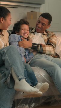 African American family at new home active son running to parents relocation funny little boy child playing with mom dad moving day happy cuddling kid mother father custody adopt insurance on sofa 
