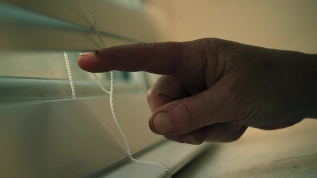 Hand opening window blinds nervously