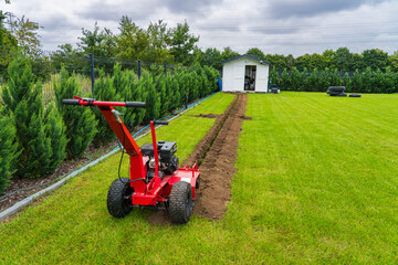 Petrol trencher used in preparatiion  for garden sprinkler system