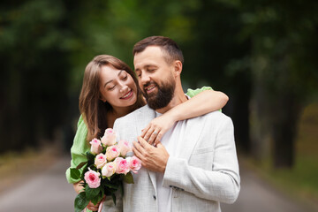 Making marriage proposal. Woman with engagement ring, flowers and her happy fiance outdoors