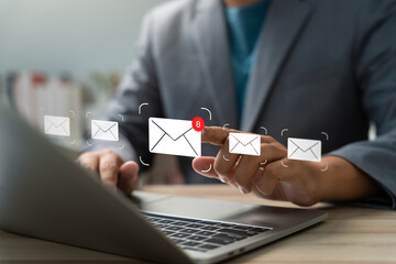 Businessman checking email notifications on laptop with digital mail icons. Concept of...