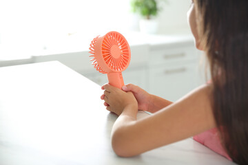 Little girl with portable fan at home, closeup. Summer heat