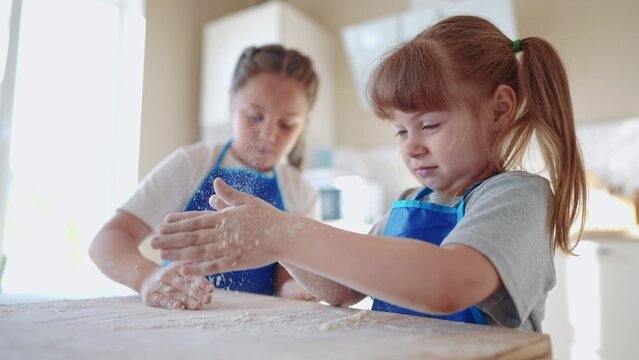 kids are baking. children knead dough and flour in the kitchen. happy family kid concept. baby children bake pizza dough. sisters baking dream cookies. teamwork children knead dough and flour