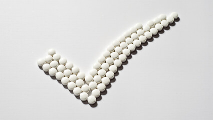 White tablets arranged in a check mark symbolize health and wellness