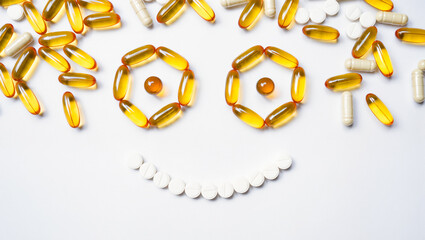 Vitamins arranged to make a cheerful face on white
