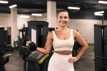 Fototapeta premium Smiling woman training with dumbbell in gym