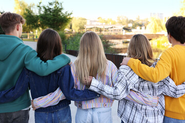Group of teenagers walking on city street, back view