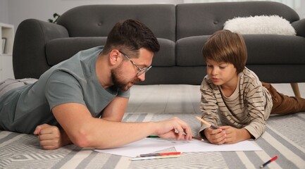 Father and son drawing together on floor at home
