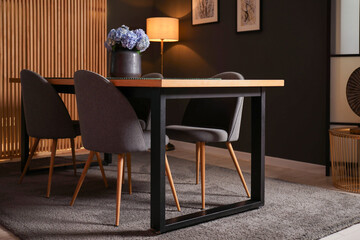 Wooden table with beautiful flowers and chairs in dining room at night