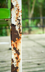 Rusty on white metal bar surface with peeling paint. Rust stains. The metal surface rusted spots. Rusty corrosion. Vertical.