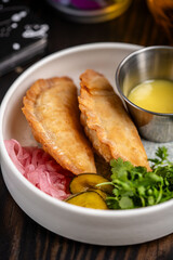 Crispy fried empanadas with pickles and herbs.
