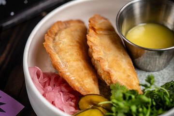 Close-up of fried empanadas with dipping sauce.