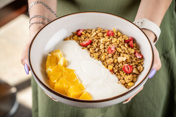 Bowl of yogurt with granola and fresh orange.