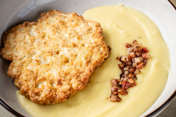 Fried cutlet with mashed potatoes and bacon topping