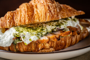Close-up of croissant sandwich with chicken and creamy pesto sauce