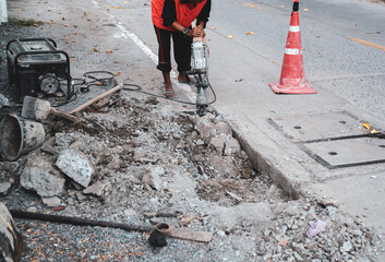 Worker demolish existing concrete road by jack hammer for repair concrete floor. Surface road...