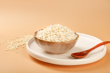 Cooked White Rice in Bowl with Wooden Spoon on Beige Background