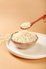 Puffed rice grains in wooden spoon and bowl on plate with warm background