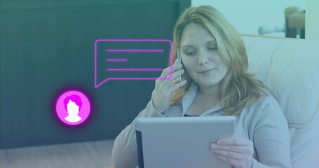 Talking on smartphone, reviewing tablet in armchair at home with chat bubble, cabinet, copy space