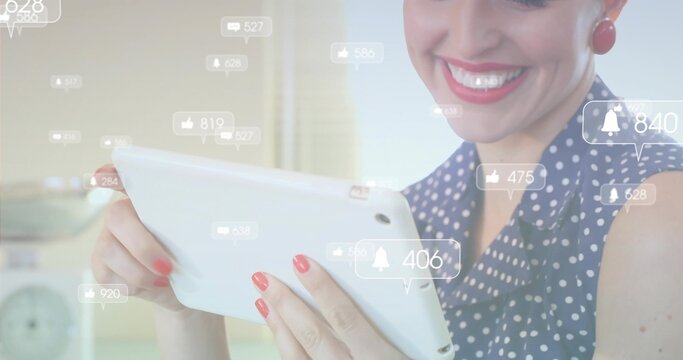 Smiling woman wearing navy blouse interacting with tablet in home kitchen, with notification icons