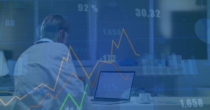 Businessman in white shirt and tie reviewing laptop in office, with financial charts and coffee cup