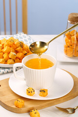 Honey drizzled into tea cup with freeze-dried passion fruit cubes on wooden serving tray