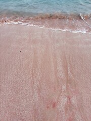 Fototapeta premium Serene pink sand beach kissed by gentle turquoise waves perfect for vacation vibes, tropical getaways, and calming coastal scenes