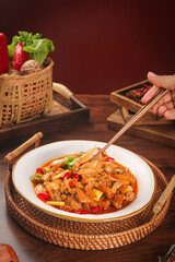 Spicy Chinese Dry Pot Beef Dish with Chopsticks and Traditional Bamboo Serving Basket on Wooden Table