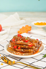 Spicy Fish Skin Jelly Dessert with Chili Peppers and Sesame Seeds on White Plate