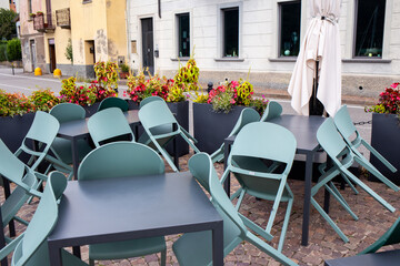 Stacked outdoor chairs and tables on cobblestone