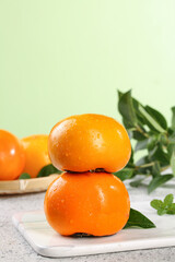 Fresh Sweet Persimmons from Fuping Shaanxi Stacked on Marble Board with Green Leaves