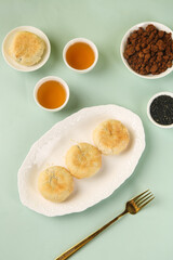 Traditional Chinese Mooncakes with Tea and Baking Ingredients on Green Background