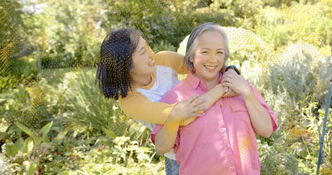 tech-themed mother with smartwatch receiving back-hug from daughter stepping in garden sharing joy
