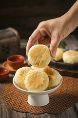 Traditional Golden Mooncakes on White Stand - Hand Selecting Asian Pastry for Mid-Autumn Festival Reunion Celebration