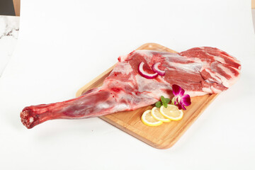 Raw Lamb Leg on Wooden Board with Lemon Garnish White Background