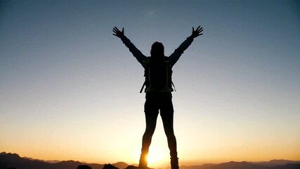 A hiker celebrates atop a mountain with arms wide open, embracing the beauty of a vibrant sunset.