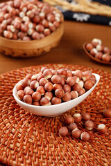 Red-skinned hazelnuts in ceramic bowl on woven basket - traditional natural nuts food photography