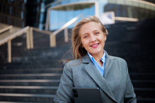 Smiling businesswoman holding tablet on steps in City Center - Powered by Adobe