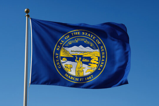 Nebraska state flag with Great Seal waving in the wind

Official flag of Nebraska featuring gold state seal on blue field

State of Nebraska banner with symbols of agriculture and industry