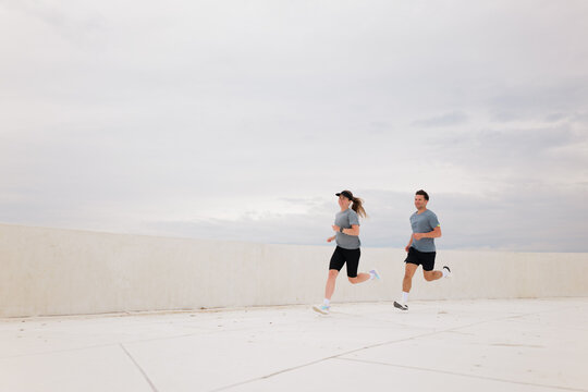 Couple running together outside on rooftop in Summer morning