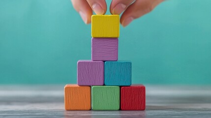 Hands stacking financial building blocks (toy blocks) on a desk, foundation, stability 
